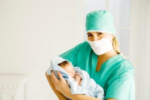A medical practitioner holding a newborn baby